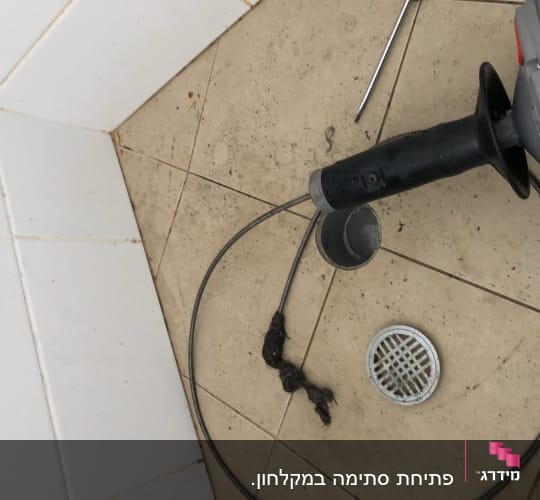 כלי עבודה לניקוי צנרת על רצפת חדר אמבטיה